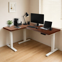 Load image into Gallery viewer, Walnut-finish solid wood L-shaped standing desk with white steel legs, styled with monitor and laptop